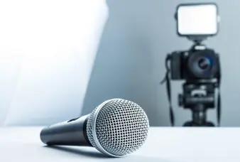 A microphone is sitting on the table in front of a camera.